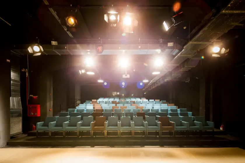 The Friendly.rb Conf 2025 venue, a theatre hall with rows of teal seats under stage lights